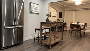A modern kitchen with a stainless steel refrigerator, a wooden cart, and a dining area with a table and chairs. - Airy Modern 2BR/2BA - Parking + Laundry + Sleep 6 (San Jose)