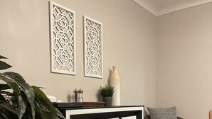 A living room with a black and white cabinet, a grey sofa, and decorative wall art. - Airy Modern 2BR/2BA - Parking + Laundry + Sleep 6 (San Jose)