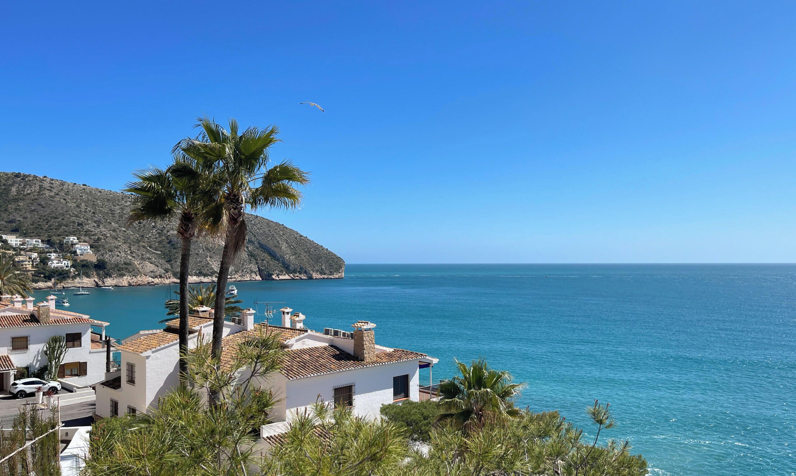 A coastal view with a clear sky, a mountain, and a body of water.