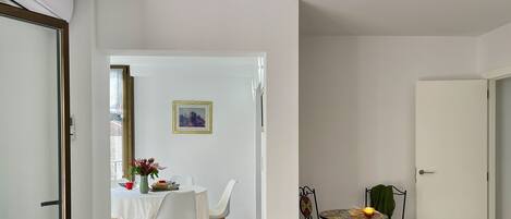 A dining area with a table and chairs, a small table with a candle, and a door leading to another room.