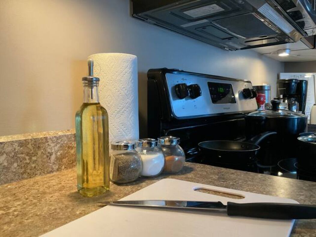 Une cuisine équipée d’une cuisinière, d’une planche à découper, d’un couteau et d’une bouteille d’huile.