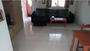 Uma sala de estar com sofá, mesa de centro e mesa de jantar de madeira.