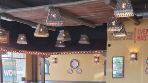 A restaurant interior with colorful chairs and tables, decorative wall art, and hanging lights. - Spacious mobile home with large kitchen/living area and porch with barbeque. (Longmont)
