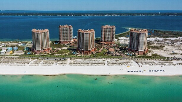 Un complexe hôtelier situé sur la côte, composé de plusieurs immeubles de grande hauteur, donnant sur la plage et offrant une vue sur l’océan.
