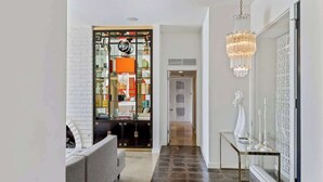 A hallway with a sofa, a glass display cabinet, a chandelier, and a patterned wall. - Mod Blue Agave - Stunning S Palm Springs Mid-Centu (Palm Springs)