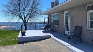 A house with a patio, a tree, and a view of the water. - Old Mill Motel (Blind River)