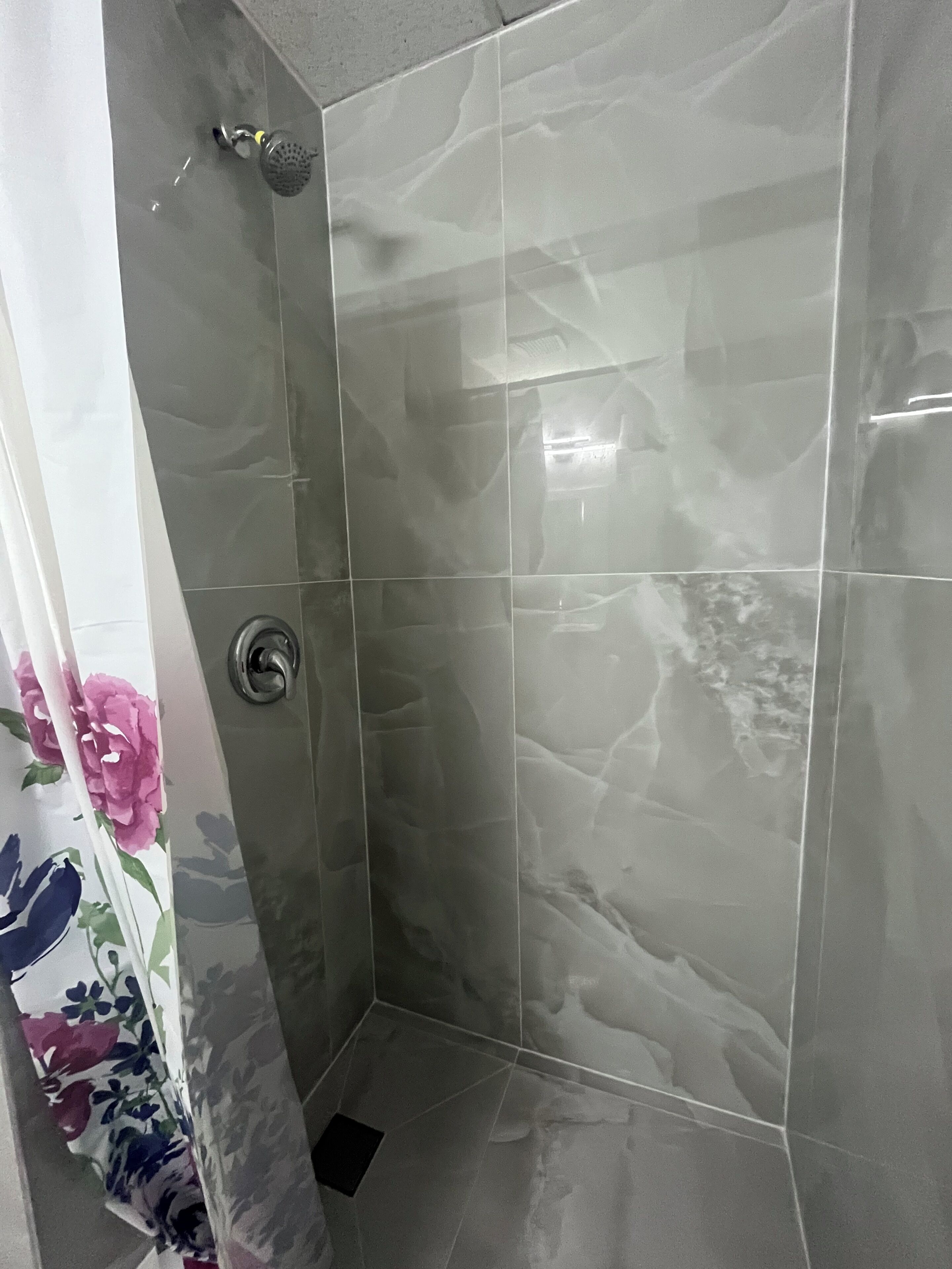 Eine Dusche mit modernem Design, ausgestattet mit einer Duschköpfe und einem Ablauf.