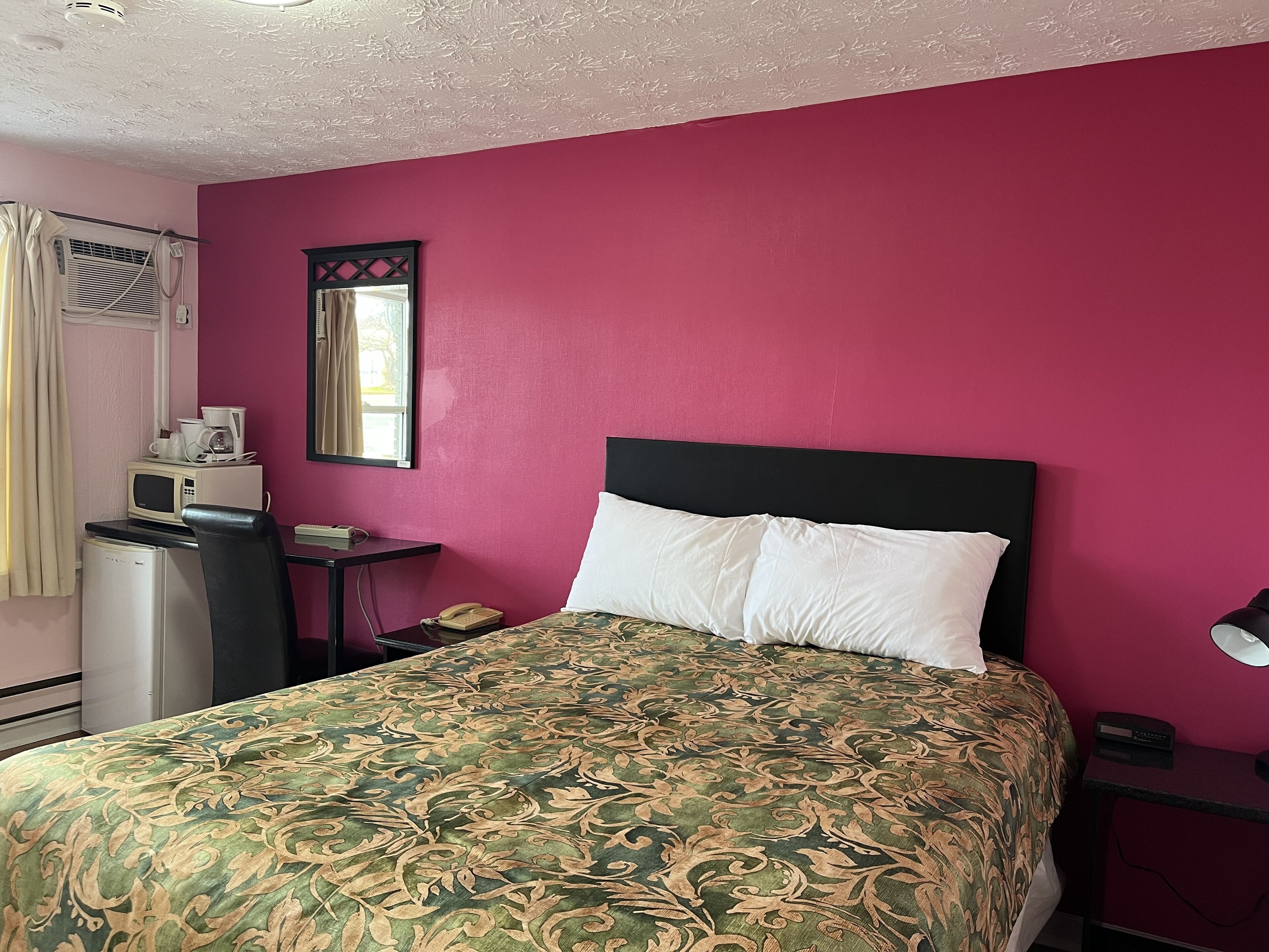 Una habitación con cama, escritorio, teléfono y microondas.