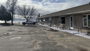 Un bâtiment avec un espace de stationnement, un camion et des bancs le long du côté.