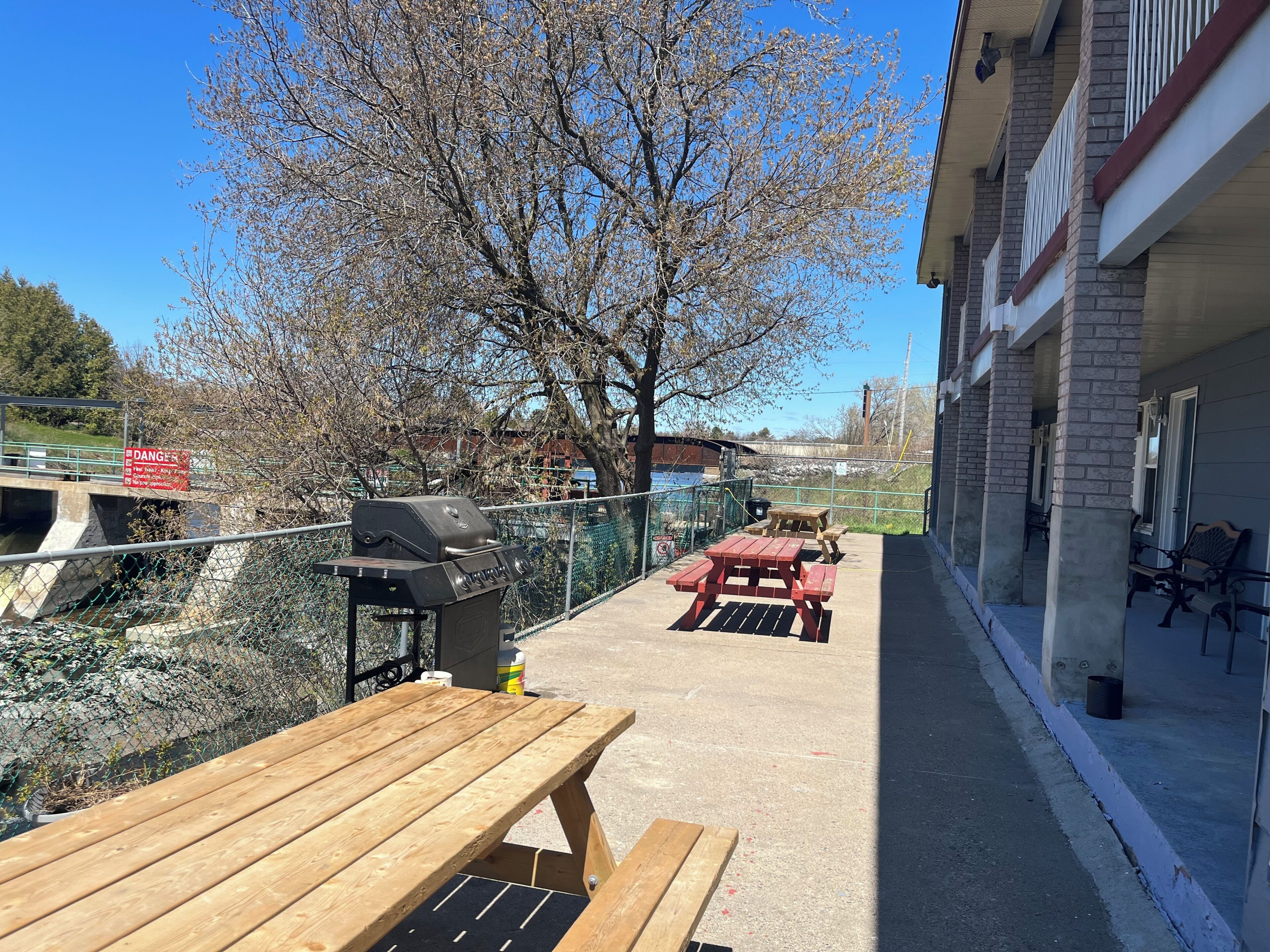 A patio with a grill, picnic tables, and a view of a river and buildings.