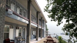 A building with a balcony, outdoor seating, and a view of the water. - Old Mill Motel (Blind River)