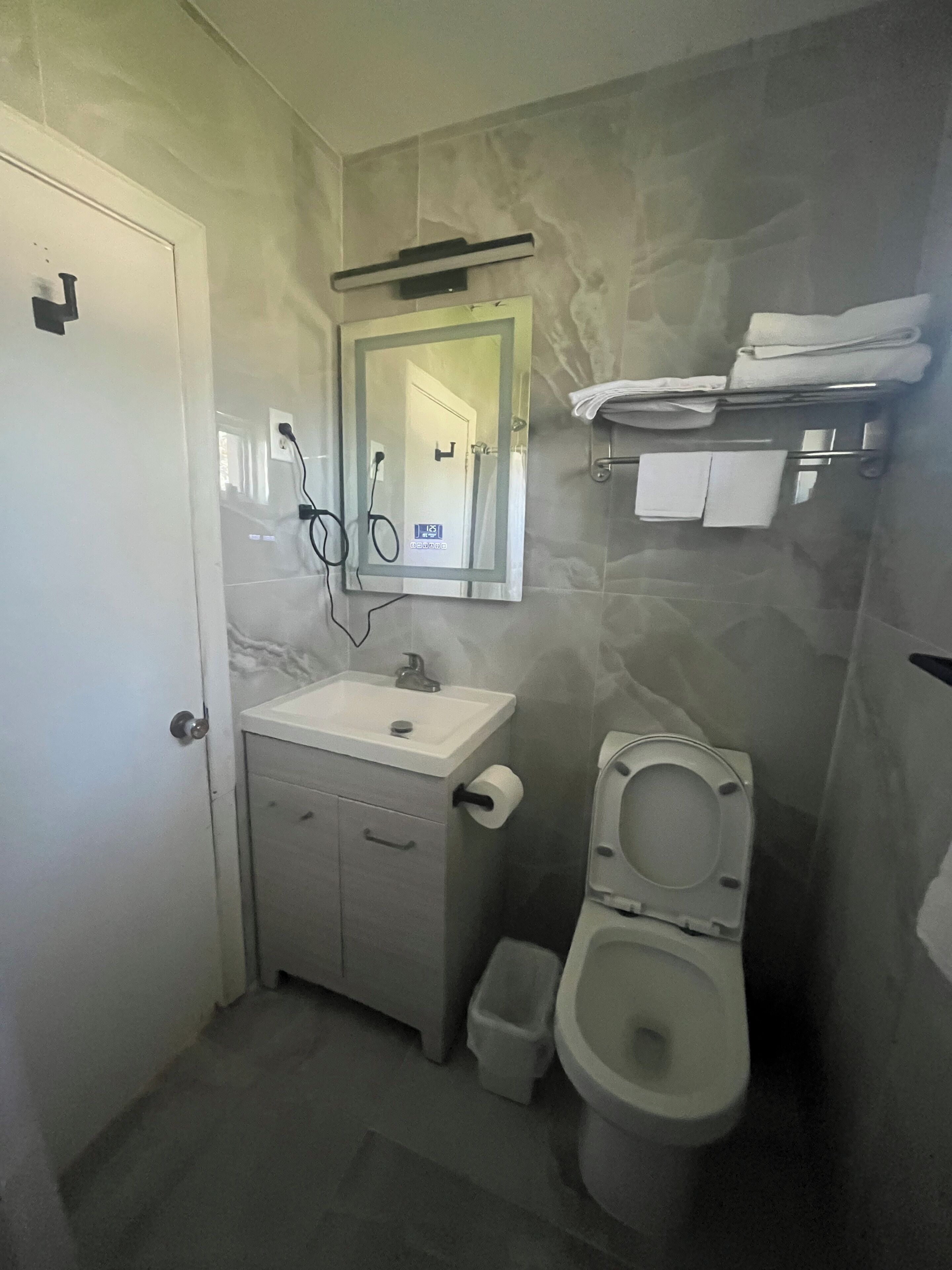 A bathroom with a toilet, sink, and mirror.