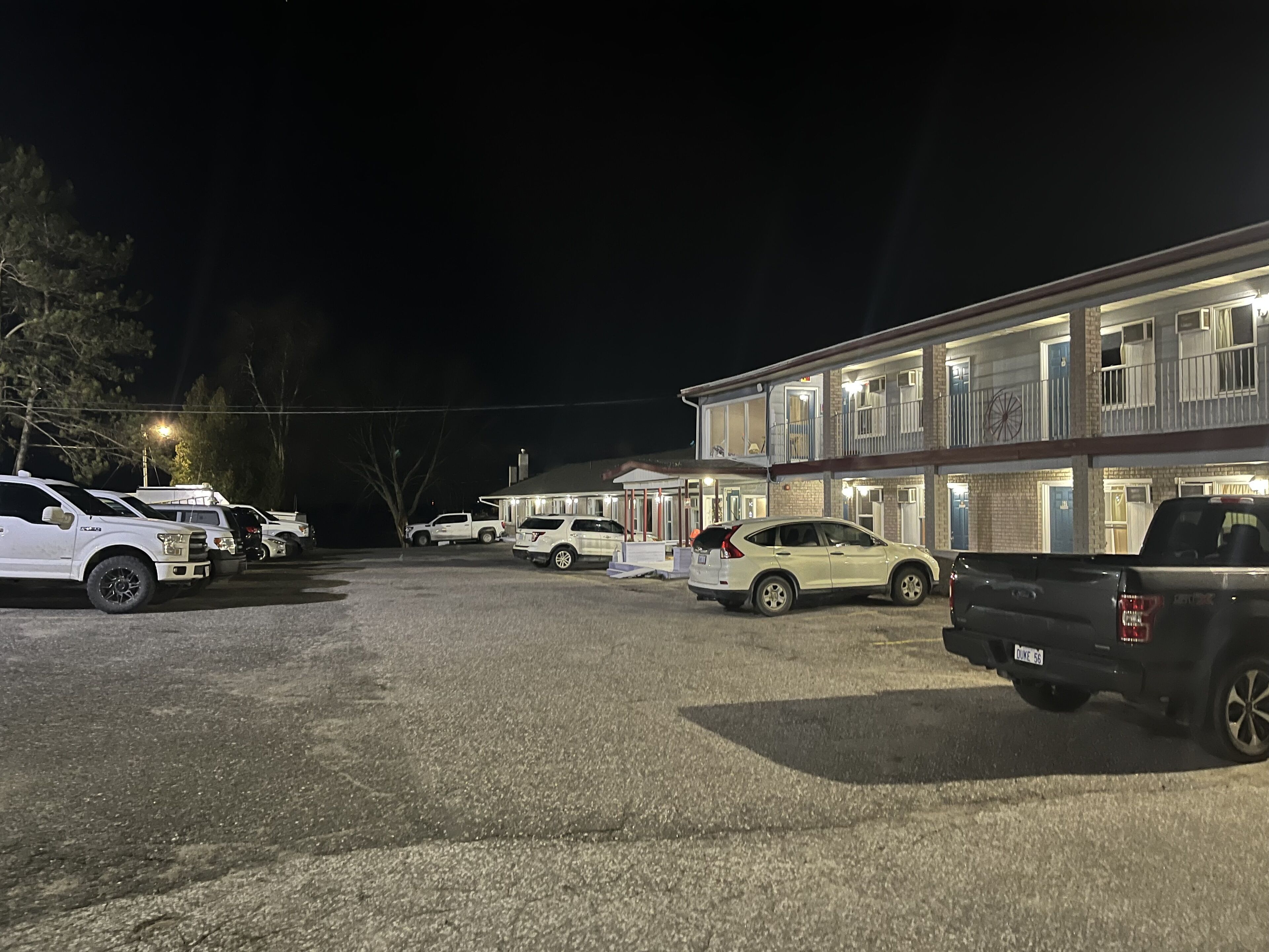 A parking lot with several vehicles, including SUVs and a truck, in front of a building with multiple windows and a balcony.