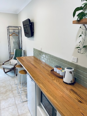 A kitchen with a wooden countertop, a kettle, and a plant.
