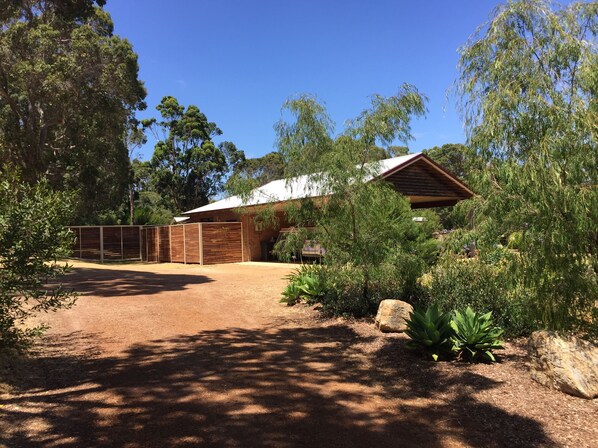 A rustic barn-style building with a dirt driveway and surrounding vegetation. - The Green Room. Self contained king suite on a beautiful property. (Margaret River)