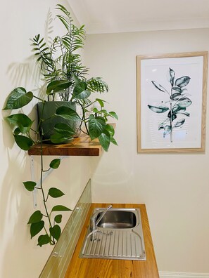 A kitchen with a wooden countertop, a stainless steel sink, and a potted plant on a floating shelf. - The Green Room. Self contained king suite on a beautiful property. (Margaret River)