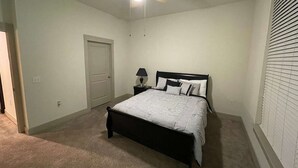 Un dormitorio con cama, mesita de noche, ventilador de techo y una puerta.