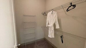 Vestidor con bata blanca colgada en un estante de alambre, una percha metálica y un estante de vidrio.