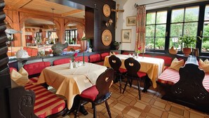 A restaurant with wooden booths, red cushioned chairs, and a tiled floor. - Vacation apartment Breitenberg approx. 50 sqm (Rottau)