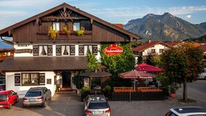 A traditional wooden building with a restaurant sign, parked cars, and a mountain backdrop. - Vacation apartment Breitenberg approx. 50 sqm (Rottau)