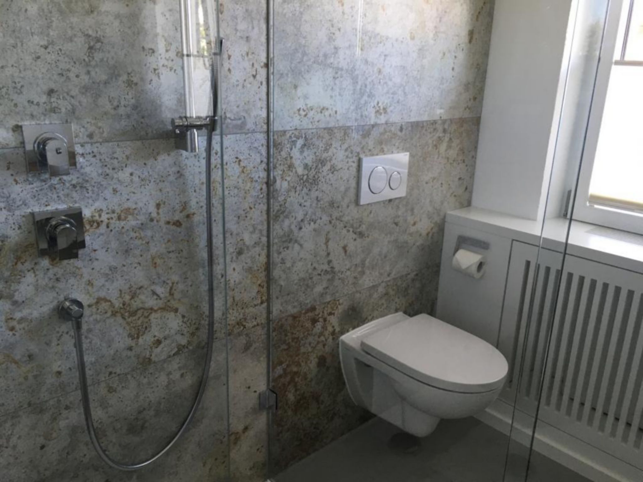 Une salle de bain avec une douche, des toilettes et un radiateur.