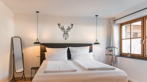 A neatly made bed with white linens, a headboard with a deer head decoration, and a bedside lamp. - Vacation apartment Steinröschen 30 sqm, 1 separate bedroom (Reit im Winkl)