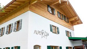 A building with a white facade and green shutters, featuring the name "ALPENBlute" prominently displayed. - Apartment Enzian 32 sqm with balcony, 1 separate bedroom (Reit im Winkl)