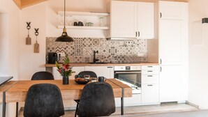 Una cucina moderna con pensili bianchi, zoccolo decorato e tavolo da pranzo in legno con sedie.