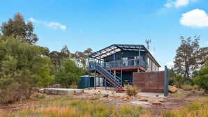 A modern house with a balcony, a staircase, and a fenced yard. - Chez Reeve - 6 National Park Road, Loch Sport (Loch Sport)