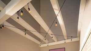 A hot tub in a corner with wooden flooring, a ceiling with exposed beams, and string lights. - Bossa Jurere Hotel (Florianópolis)