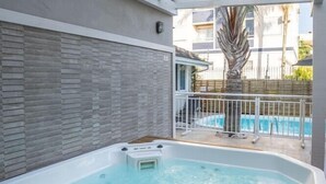 A hot tub under a pergola with a brick wall and a pool in the background. - Bossa Jurere Hotel (Florianópolis)