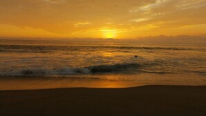 Une plage avec des vagues et un coucher de soleil.