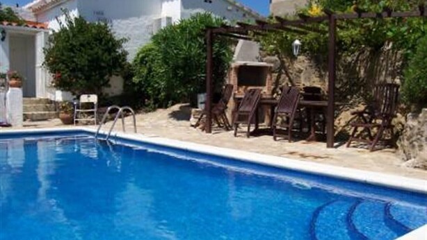 Una piscina con muelle de madera y sillas de descanso.