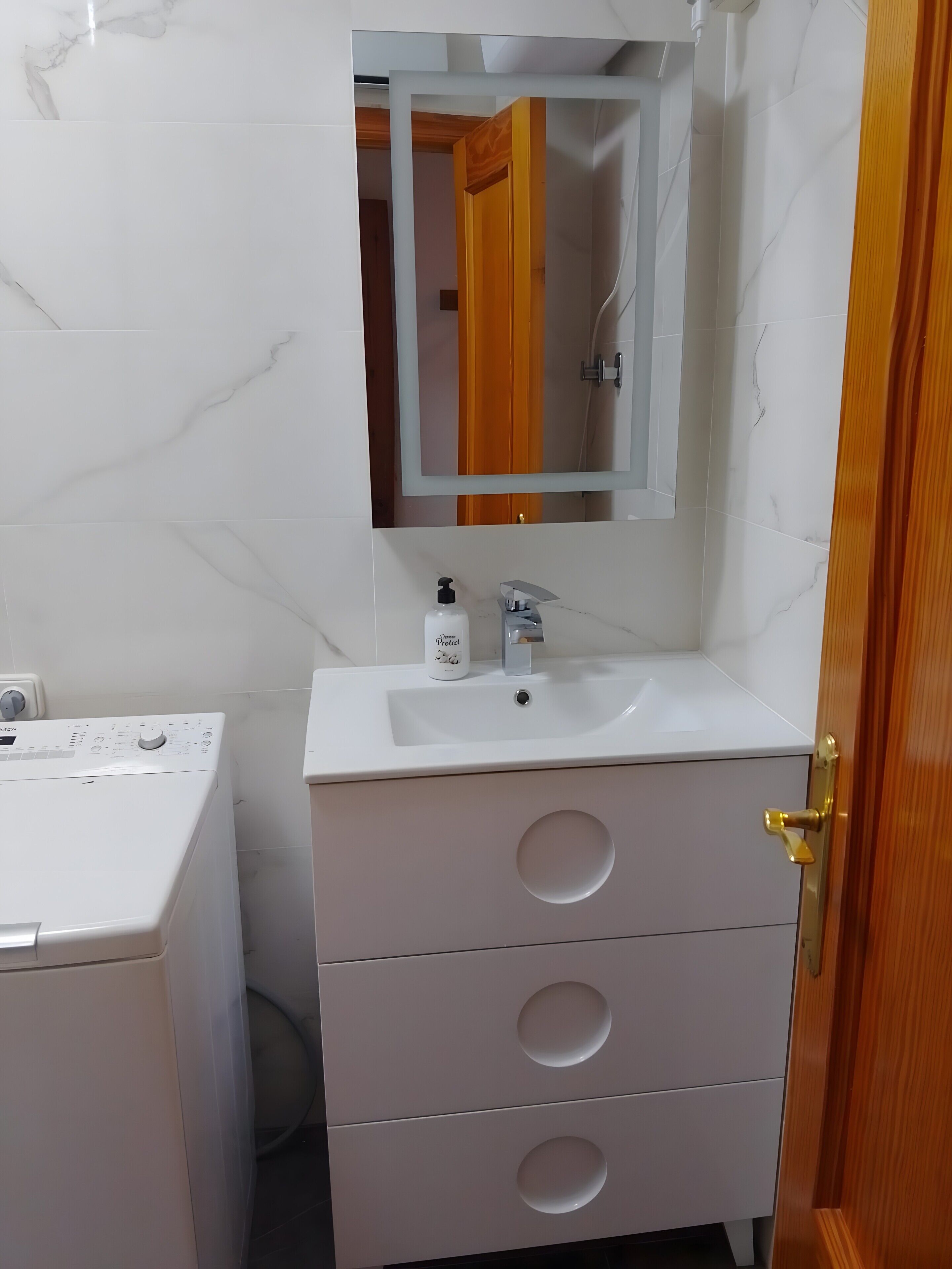 A bathroom with a white sink, mirror, and a Bosch washing machine.