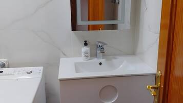 A bathroom with a white sink, mirror, and a Bosch washing machine.