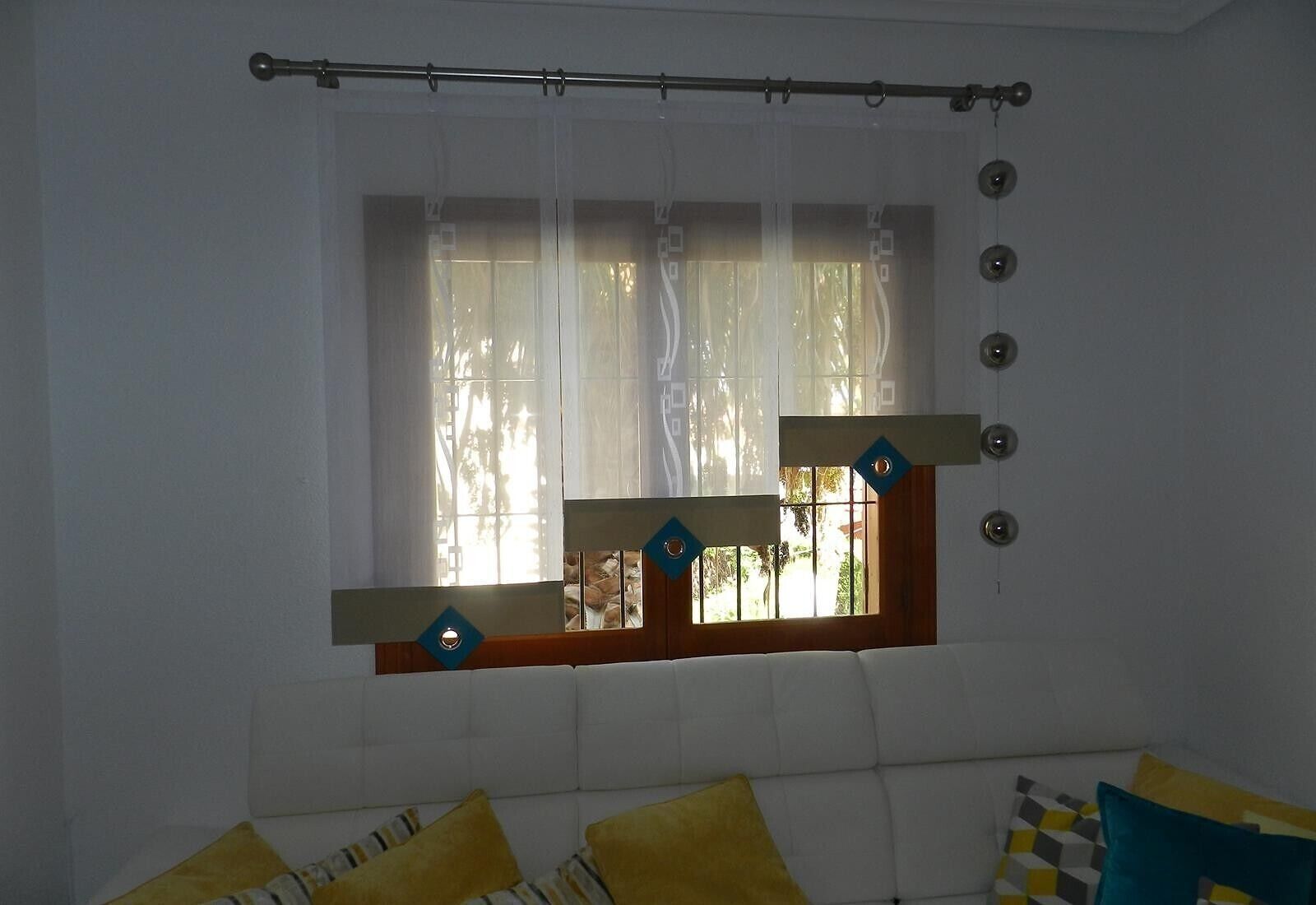 Una habitación con ventana, una barra para cortinas y una cama con almohadas.