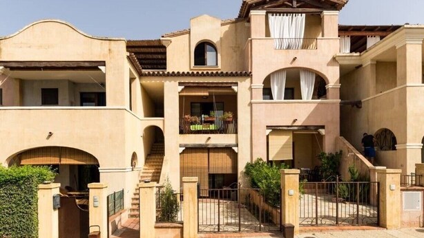 A multi-story building with a central courtyard, balconies, and a gated entrance. - Apartment Perugino with Terrace, Balcony, A/C & Wi-Fi (Villasimius)