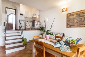 Un coin repas avec une table en bois, des chaises, une plante en pot et une carte accrochée au mur.