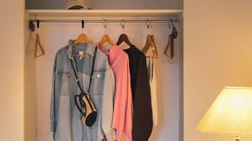 Ein Hotelzimmer mit Schrank, Kleidungsstücken zum Aufhängen und einem Koffer.