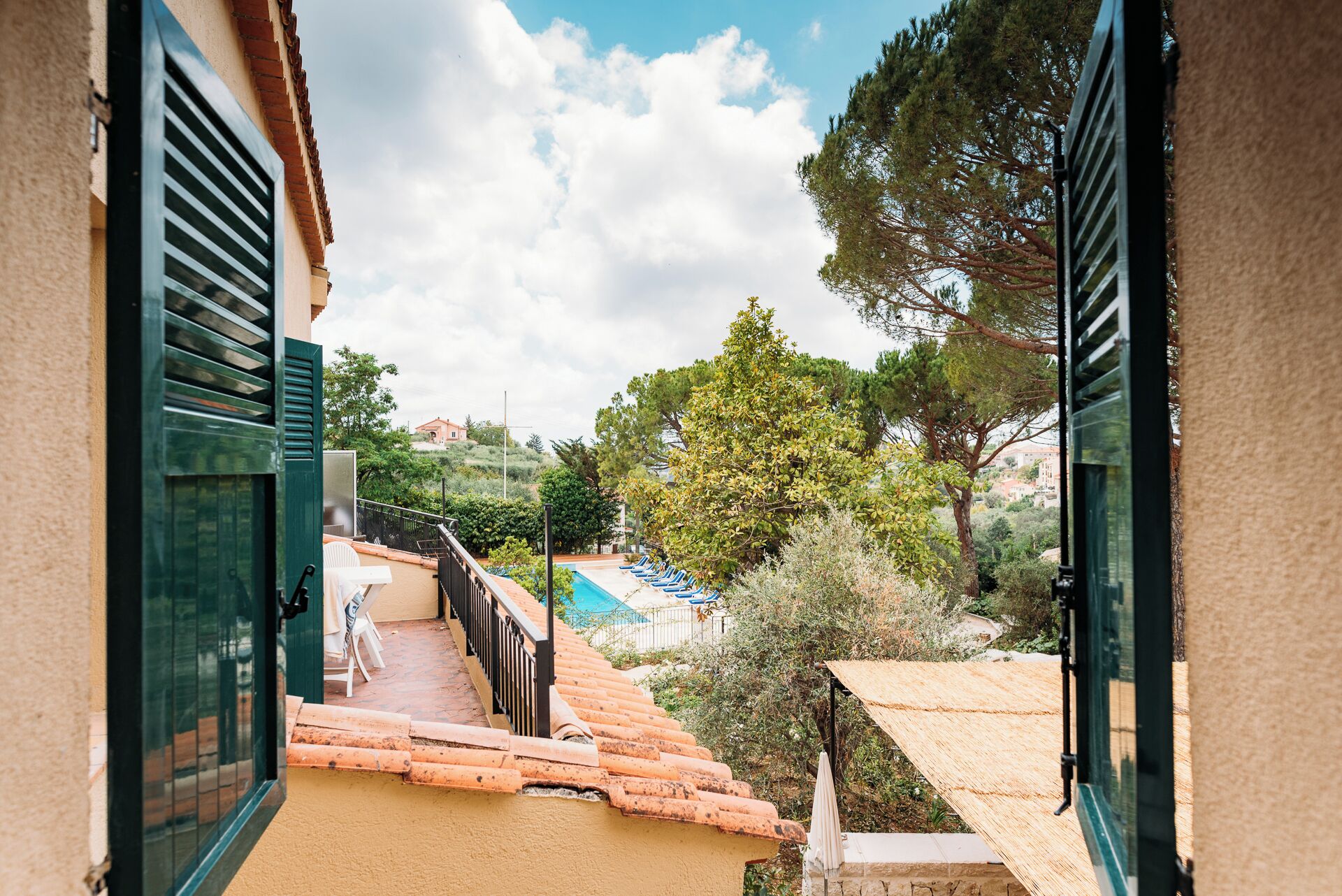 Blick von einem Balkon mit Pool, Sitzgelegenheit im Freien und einer Hügelkulisse im Hintergrund.