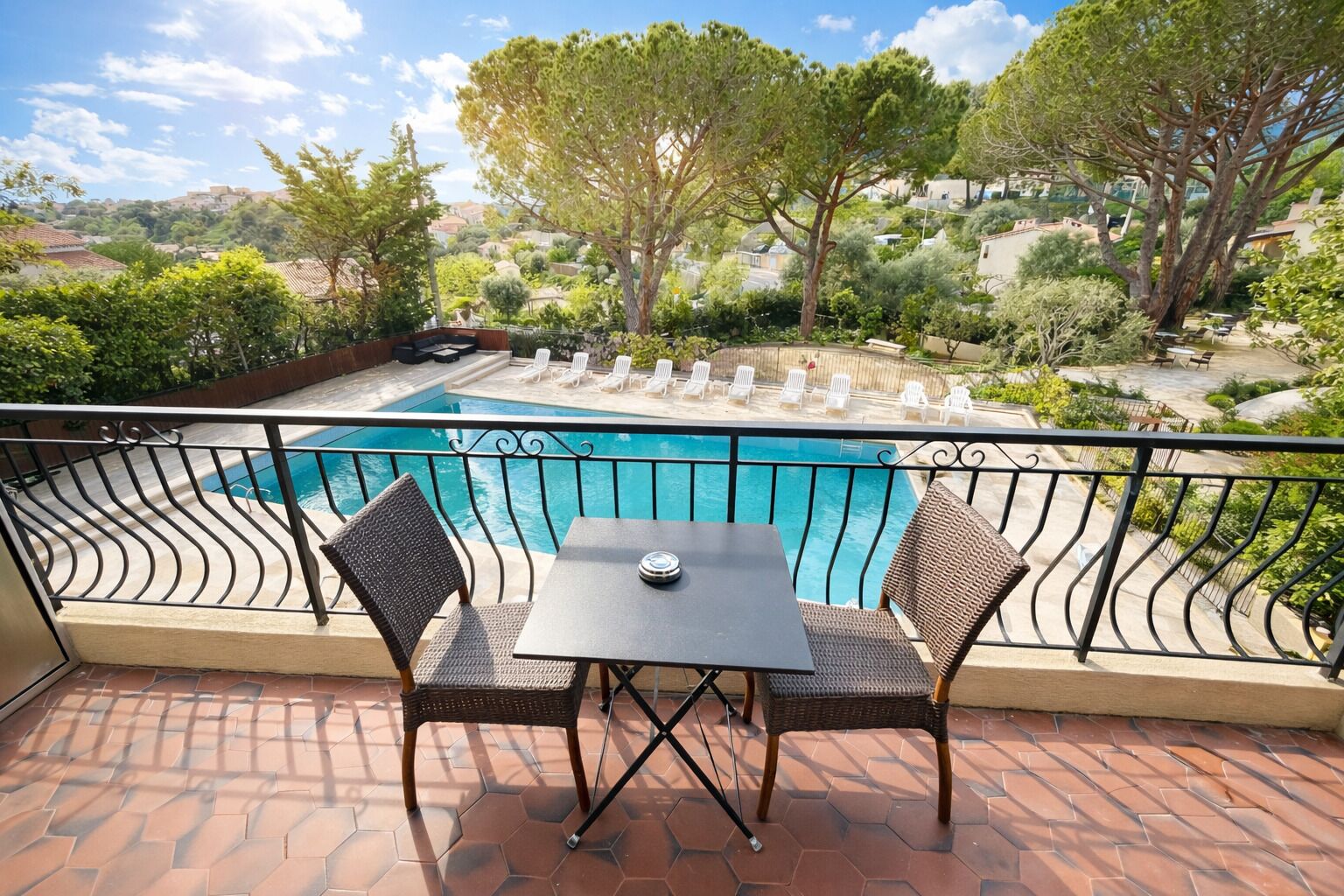 A balcony with a pool, wicker chairs, and a table.