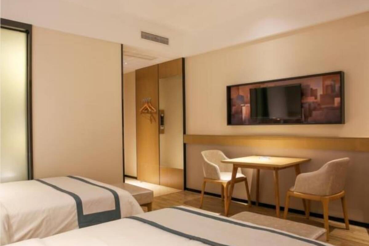 Ein Hotelzimmer mit zwei Betten, einem Fernseher, einem Tisch und Stühlen.