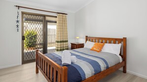 A bedroom with a wooden bed, a nightstand, a lamp, and a view through a door with a metal gate. - Pet Friendly / Stroll to the beach (WOORIM)