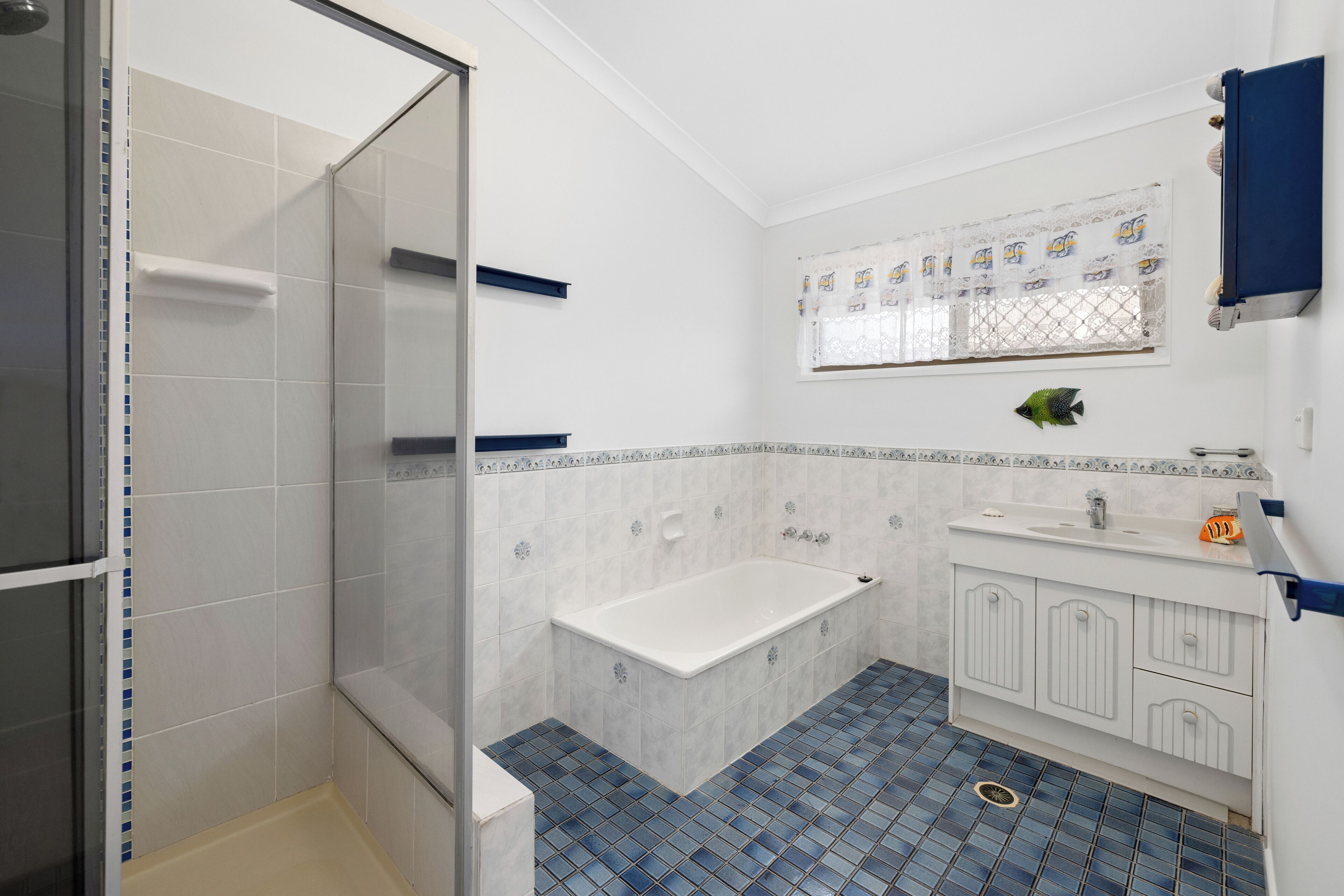 Une salle de bain avec une douche à parois de verre, une baignoire, un lavabo avec un miroir au-dessus et un sol carrelé.