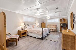 Un dormitorio con cama, mesitas de noche, cómoda, cuna y televisor.