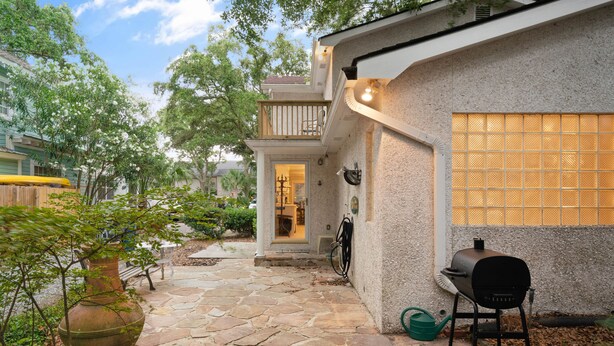 A stone-paved patio with a large vase, a grill, and a bench. - Byrd's Nest is located across the street from the beach and sleeps 10 (St Simons Island)