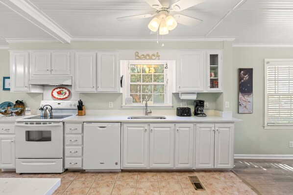 Una cocina con armarios blancos, estufa y lavabo.