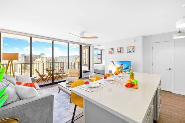 A modern kitchen with a large island, dining area, and a city view.
