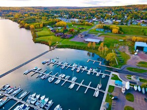 An aerial view of a marina with multiple docks and boats, surrounded by a residential area with houses and greenery. - Updated Suite in great location close to Bayfield, the Apostle Islands, and more (Washburn)