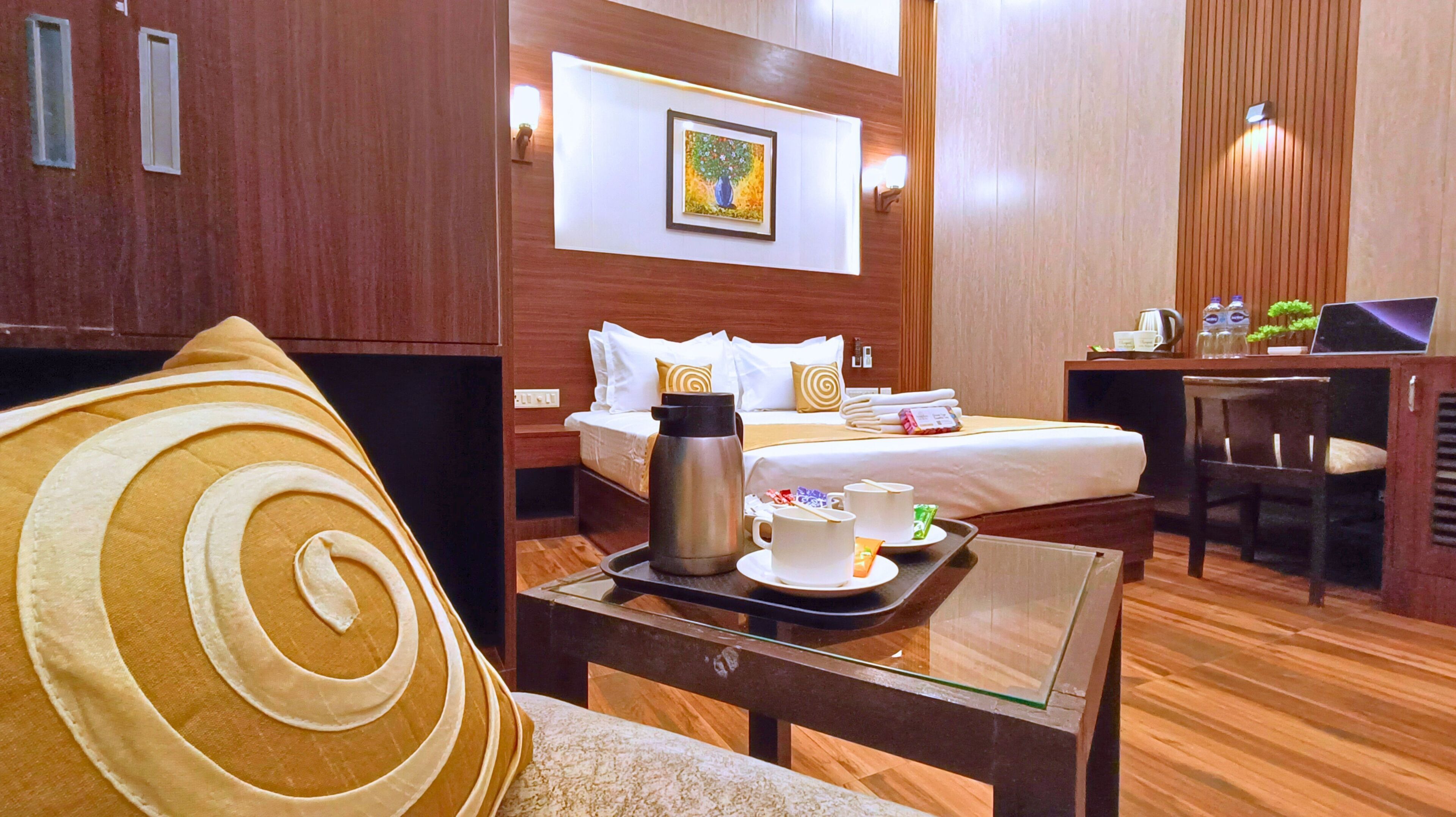 A hotel room with a bed, a desk, a chair, a coffee table, and a pillow.